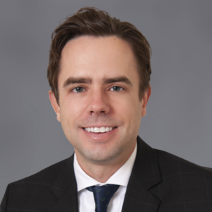 An closely cropped professional portrait of Ross Stadheim, employment attorney. He wears a black suit and gazes into the camera with a confident smile.